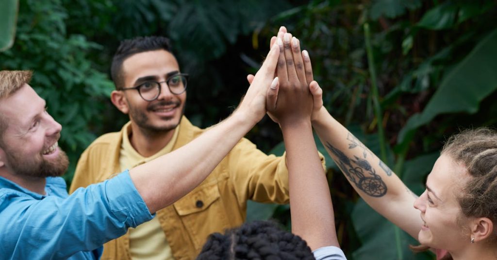 pexels-photo-3228685-3228685 A joyful group of friends high-fiving outdoors, symbolizing teamwork and camaraderie.